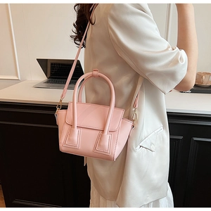 Detail of pink faux leather handbag with adjustable strap shown in office setting