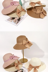 Detail of wide brim straw sun hat featuring elegant satin bow and pearl accents