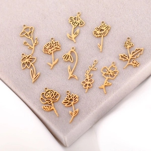 Golden stainless steel birth flower pendants set displayed on a beige velvet stand