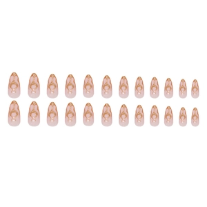 Almond-shaped press-on nails with nude pink base and golden glitter flame patterns