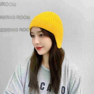 Detail view of bright yellow ribbed knit earflap hat for winter windproof protection