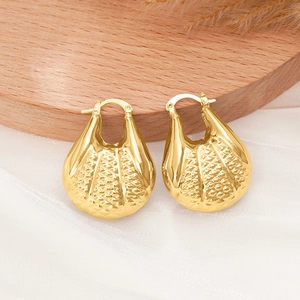 Détail de boucles d'oreilles dorées avec texture quadrillée et fini poli sur bois
