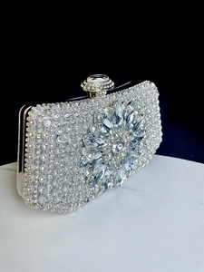 Detailed side view of silver evening clutch with sparkling rhinestones and floral crystals
