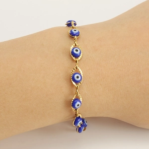 Macro shot of gold-plated stainless steel evil eye bracelet with blue charms on wrist