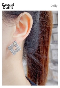 Detail view of geometric silver earrings with zircon pavé worn by a model for daily use