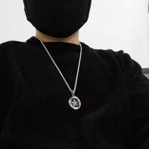 Close-up of a silver pentagram star pendant necklace worn by a model in black outfit