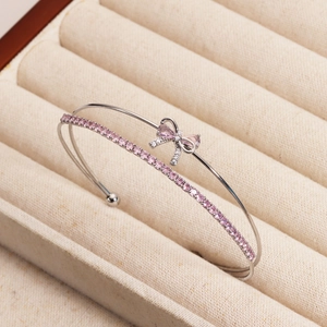 Detail of a silver bow bracelet with pink zircons and double-layer open design