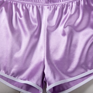 Detail of purple satin sports shorts showing white trim and premium fabric texture