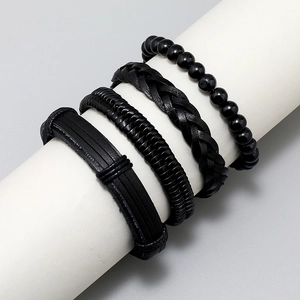 Set of four black leather and beaded bracelets displayed on a white cylindrical stand