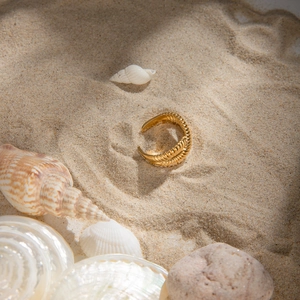 Anello aperto a spirale in acciaio placcato oro 18k su sabbia con conchiglie