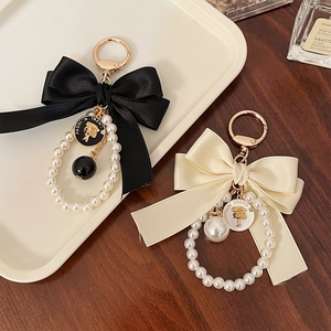 Elegant silk bow keychain with faux pearls and embossed charms in black and white