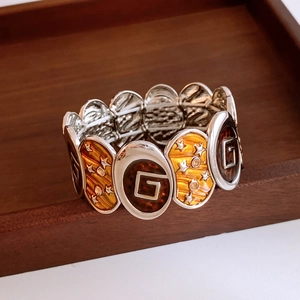 Detailed macro shot of vintage elastic bracelet with orange star and enamel G pattern