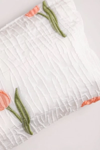 Detailed macro view of white pleated fabric with orange tulip embroidery on the pouch