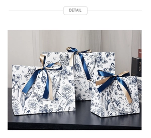 Detailed view of floral gift bags set with blue satin ribbons on a dark wood surface