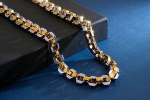 Macro detail of industrial style gold and silver mixed chain necklace with hexagonal links