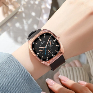 Detail of rose gold square watch with black silicone strap on a model wrist