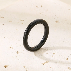 Polished black ring on stone background, featuring a sleek minimalist design and 18k gold accents