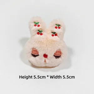 Detail of plush beige bunny charm with red cherry embroidery measuring 5.5cm by 5.5cm