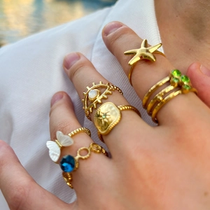 Close-up of gold stainless steel rings with natural shell and star motifs on fingers