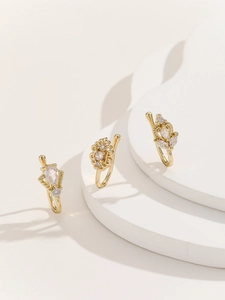 Detail of three gold nose clips with intricate openwork and sparkling zircon heart inlay