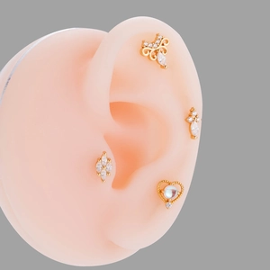 Detailed view of four gold screw back ear studs with zircon heart and butterfly on ear model