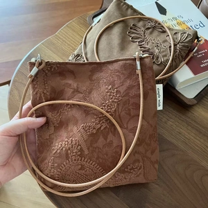 Gros plan détaillé des broderies florales sur les sacs à bandoulière en daim camel