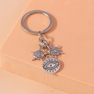 Macro shot of silver sun and eye charm pendants on a metallic keychain link