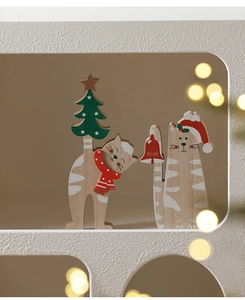 Detail of wooden Christmas cat figurines with red scarves in a warm festive setting