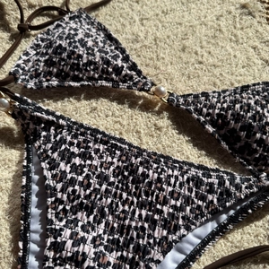 Detailed texture of smocked bikini fabric with leopard print and pearl bead accents