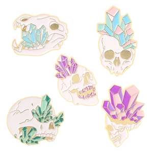 Five punk style crystal skull enamel pins with pastel colors and gold metal plating