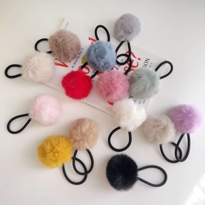 Colorful plush pom pom hair ties set on white background with fashion magazine