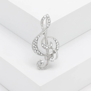 Silver treble clef brooch with sparkling rhinestones on a white geometric background