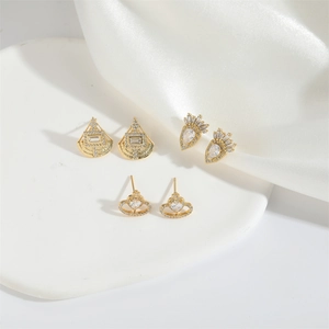 Luxurious gold studs set with fan, crown, and heart planet designs on white silk