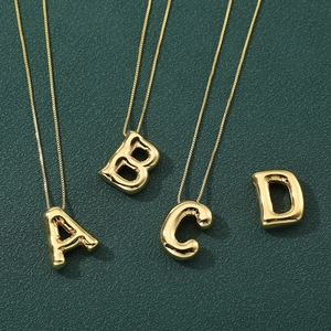Detailed macro view of 3D balloon-style gold letter A-D pendants on cross chain
