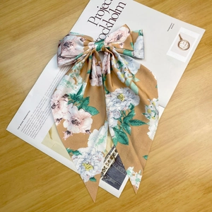 Detailed view of floral satin bow hair clip with ribbons on an aesthetic background