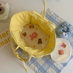 Top view showing a yellow quilted tote bag with a cartoon lunch box inside on a table