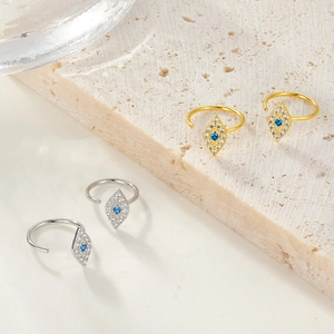 Macro shot of gold and silver devil eye hoop earrings on textured stone surface