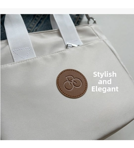 Détail d'un sac cabas en toile blanc cassé avec écusson cuir et anses tissées