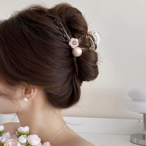 Detail of jelly brown flower hair claw clip with pearls worn in a high bun hairstyle