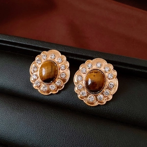 Dettaglio di orecchini vintage a fiore con occhio di tigre ovale e cristalli