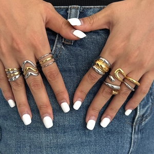 Close-up of minimalist gold and silver stacked rings on hand with denim background
