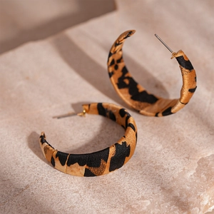 Macro shot of leopard print fabric wrapped C-shaped hoop earrings on stone background