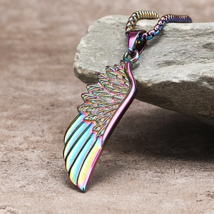 Macro detail of rainbow stainless steel feather pendant on a grey rock surface
