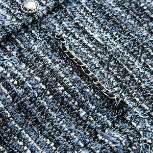 Vue détaillée du tissu en tweed bleu avec bordure en chaîne et bouton décoratif