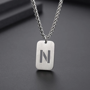 Détail du pendentif rectangulaire argenté avec lettre N évidée sur une chaîne maille