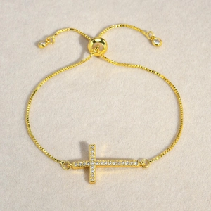 Close-up of golden cross bracelet with sparkling zircons and adjustable box chain