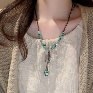 Close-up of ethnic beaded necklace featuring a silver butterfly pendant and green beads