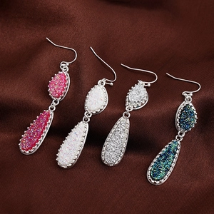 Sparkling crystal cluster drop earrings in four colors on elegant dark brown silk background