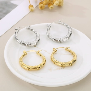 Close-up of bamboo-style U-shaped hoop earrings in gold and silver stainless steel
