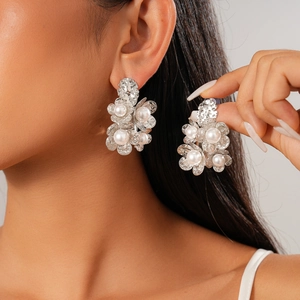 Elegant flower earrings with white pearls and silver finish shown on a model
